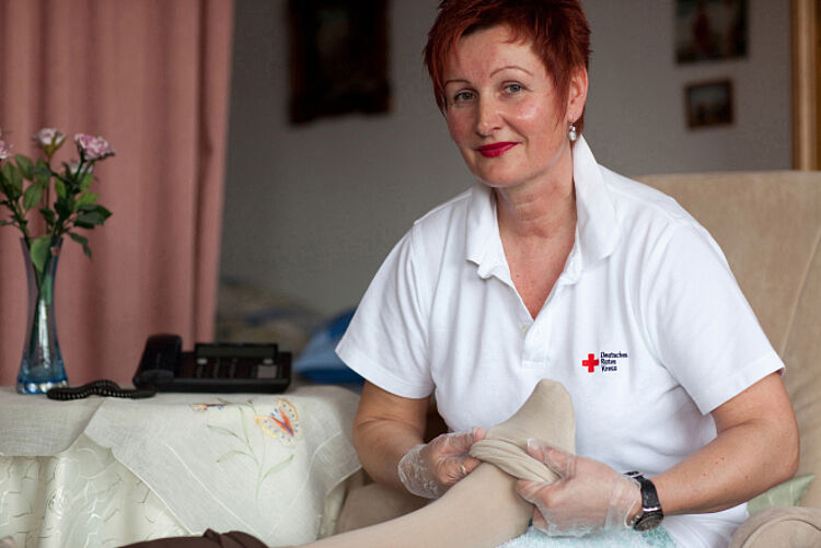 Pflegerin zieht einer älteren Person die Strümpfe an